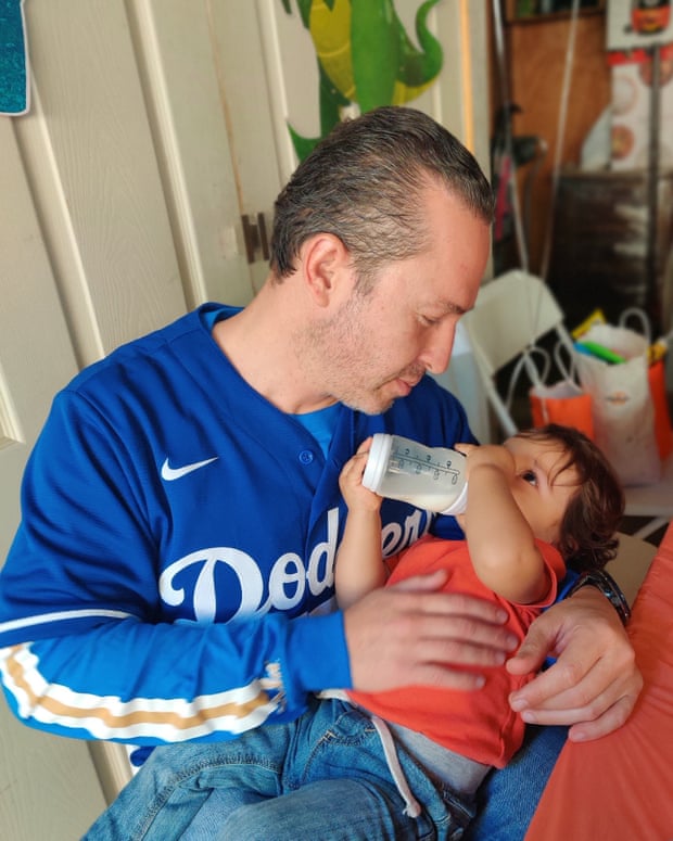 Un hombre amamanta a un bebé en su regazo a través de un biberón
