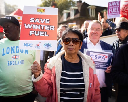 A woman holds a sign saying ‘save winter fuel’ at a protest