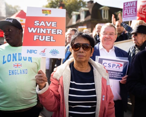 A woman holds a sign saying ‘save winter fuel’ at a protest