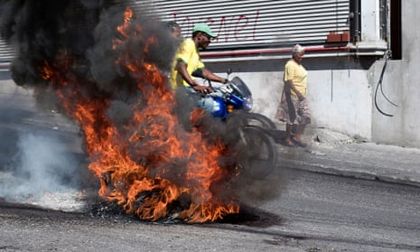 A motorcycle passes a roadblock of burning tyres near Port-au-Prince’s Toussaint Louverture airport during demonstrations against the government of President Jovenel Moïse