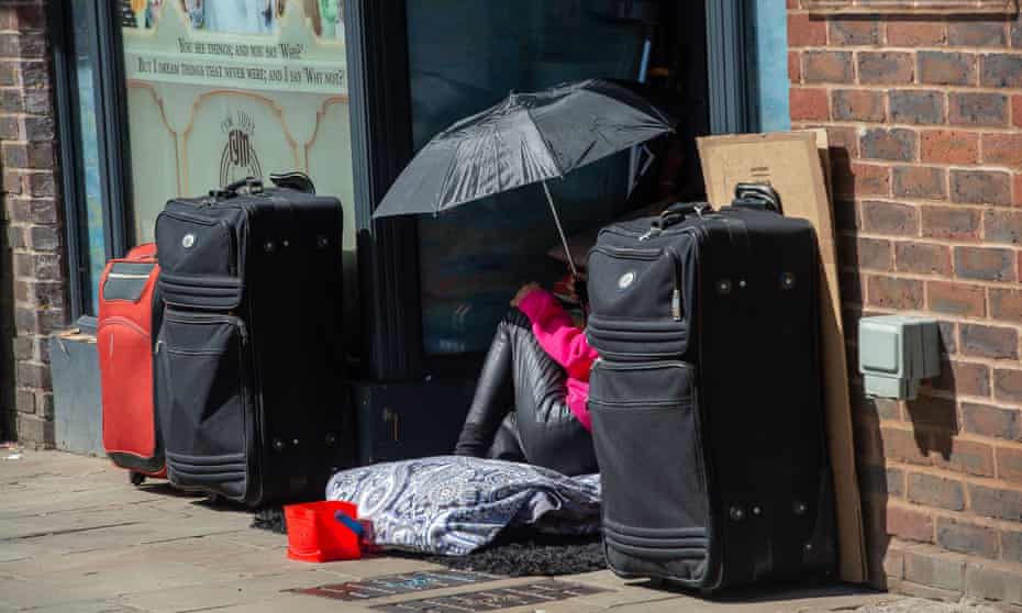 A homeless woman sits in a closed restaurant foyer with her cases.
