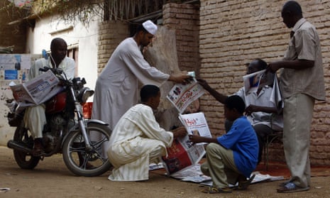 Sudanese men gather around a newspaper street vendor outside Khartoum, 2015.