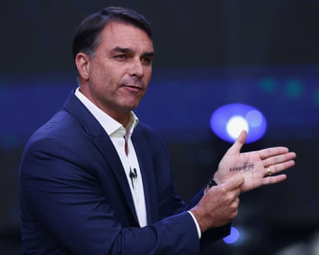 Flavio Bolsonaro gestures, pointing to the word "corrupt" written on his palm during a debate