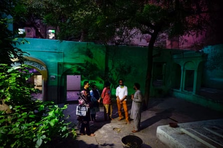 A guide talks to a small group in a floodlit courtyard .