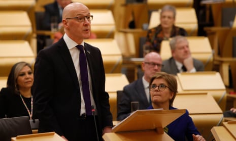 John Swinney, next to Nicola Sturgeon, delivers the Scottish budget to the Scottish parliament in Edinburgh.