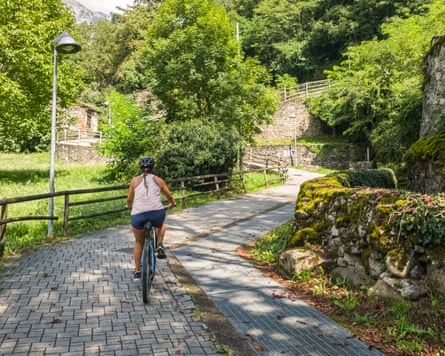 Woman cycling in Chiavenna. Valchiavenna, Sondrio province, Italy. Female tourist cycling on a paved bicycle lane in summer in the outskirts of the town of Chiavenna, Sondrio province, Italy.