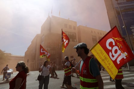 Protesters hold red and yellow CGT union flags during a demonstration in a Marseille street