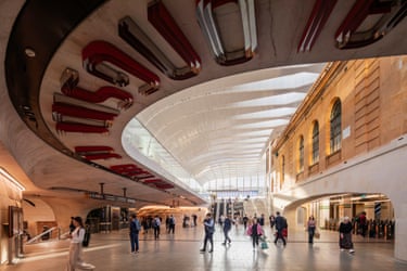 Travellers walk through Central Station’s concourse with a curved white ceiling and red sculptural detailing