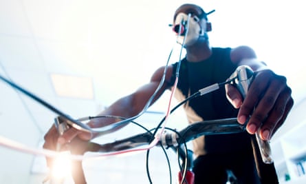 A man riding a stationary bike in a lab wearing various biometric monitors