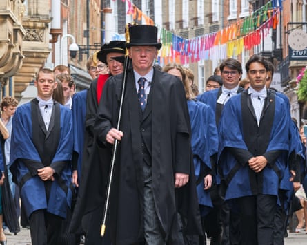 Students from Trinity College, lead by a mace bearer, process from their college to Senate house, University of Cambridge.