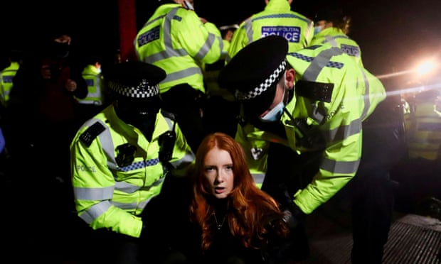 Police detain a woman as people gather at a memorial site in Clapham Common Bandstand, following the kidnap and murder of Sarah Everard, in London on 13 March 2021.