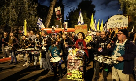 Protest for the release of hostages: people hold signs, flags, and bang drums.