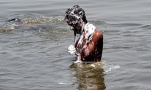 An Indian man bathes in the polluted waters of the river Yamuna in New Delhi