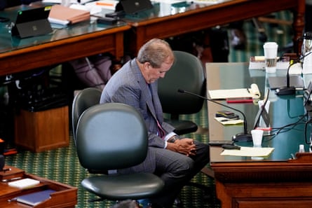 a man sits in a chair with his head bowed