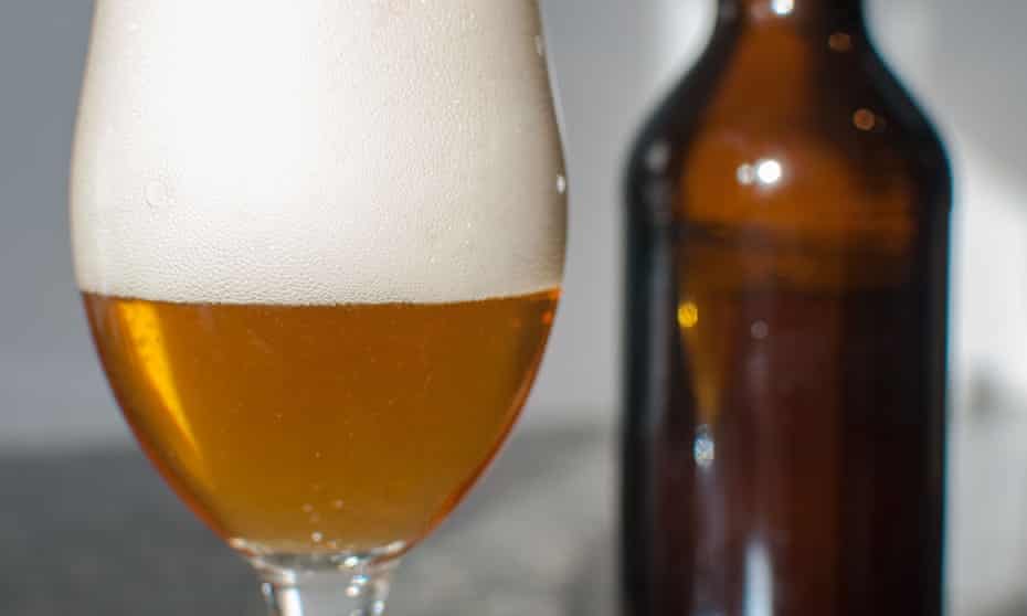 close up of a light brown beer in a glass and a brown beer bottle