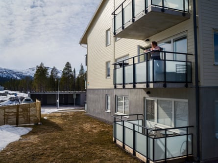 Johansson stands on the first floor balcony.  Other balconies above and below her.  Forest landscape in the background