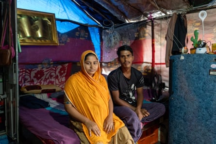 A woman and a man sit on a bed.