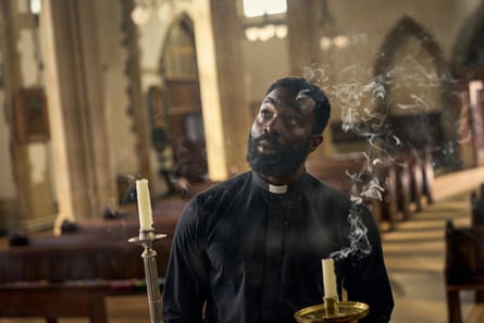 A priest holds a smoking candle in a church.
