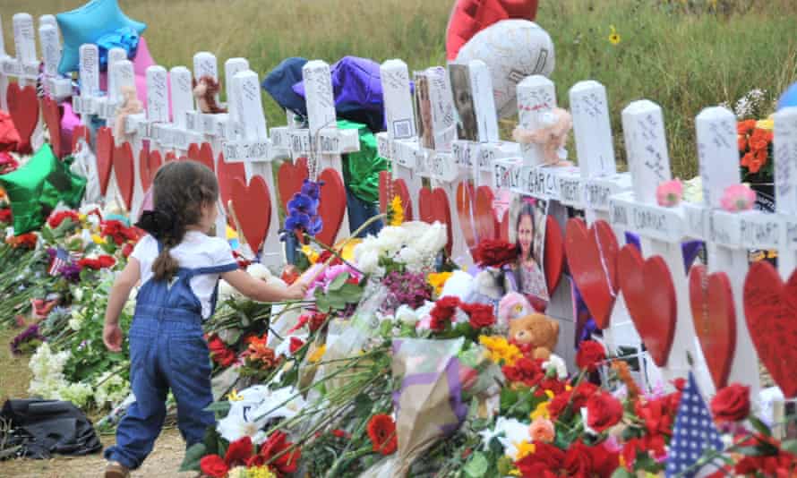 A girl lays flowers at a memorial site for victims killed in a mass shooting in Sutherland Springs, Texas on 12 November 2017.