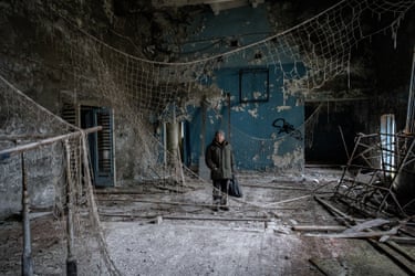 Volodimyr Verbitsky stands amid rubble and torn netting in Chernobyl-2's abandoned gym