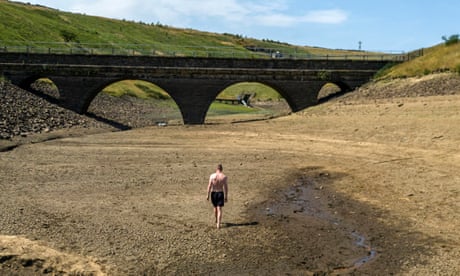 A man walks along a dry bank of a tributary to the Dowry Reservoir close to Oldham, Greater Manchester, on Monday