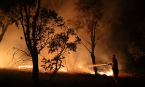 A firefighter works to extinguish flames after a bushfire burnt through the area in Bredbo