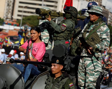A civilian holds a weapon alongside members of the Bolivarian militia and the national armed forces on top of a tank during a rally in support of the Venezuelan president, Nicolas Maduro, in Caracas