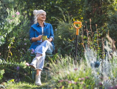Senior woman relaxing in her garden with a cup of tea in her hand
