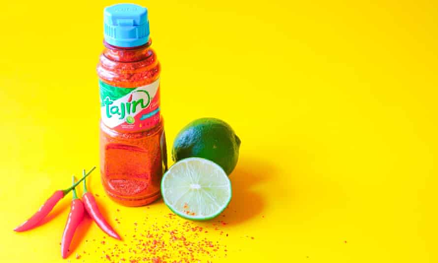 Tajin Mexican seasoning made from chili, lime and sea salt with fresh cut limes and cayenne peppers .