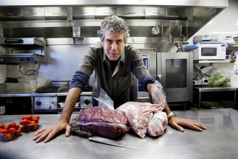 A chef standing in front two huge slabs of meat on a silver table
