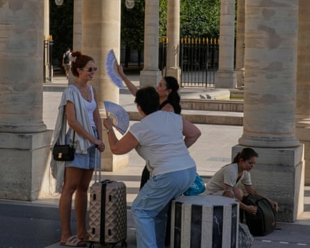 A tourist is fanned by friends at the Palais-Royal gardens in Paris, France.