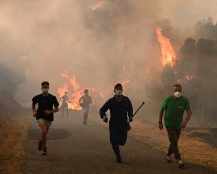 Men wearing face masks run through thick smoke as trees burn behind them