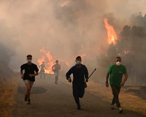 People run by a burnt area during a wildfire near the village of Larouco, in the province of Ourense, in northwestern Spain.