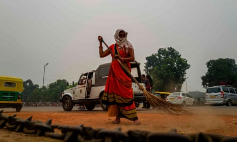 A woman sweeps a street near India Gate under heavy smog in Delhi