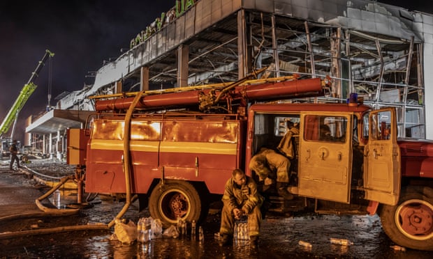 Firefighters rest after working through the night, following a missile strike on a shopping centre in Kremenchuk, central Ukraine.