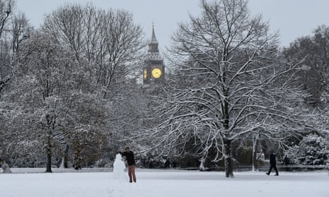 A person builds a snowman near the Palaces of Westminster