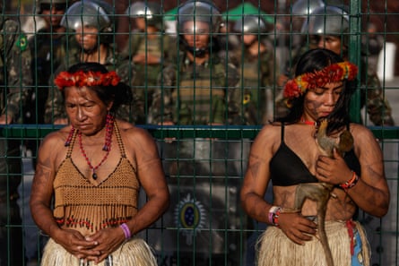 Two women stand in front of police in riot gear