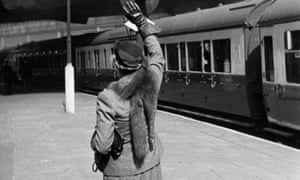 A lone woman stands on an empty platform waving goodbye to a departing troop train, 1942.