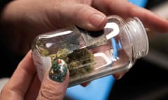 A customer looks at cannabis buds in a glass jar