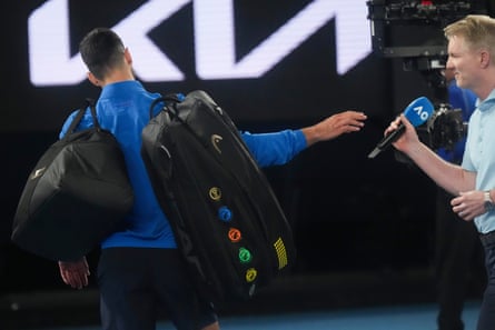 Djokovic hands the microphone back to Jim Courier after his match against Jiri Lehecka.