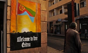 A man waits to cross the road beside a patriotic poster in Asmara, Eritrea, on July 18, 2013