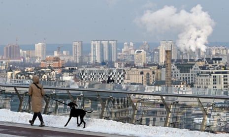 A woman walks a dog after snow fall in Kyiv.