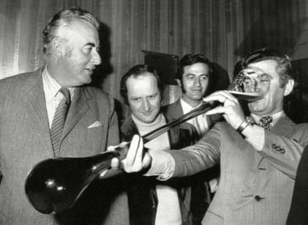 Bob Hawke drinking from a yard glass, as then-prime minister Gough Whitlam watches