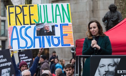 Stella Assange addresses her husband’s supporters outside the court: she is standing in front of a large banner reading Free Julian Assange, and wears a dark green coat
