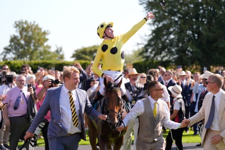 Billy Loughnane on Bow Echo throws his goggles to the crowd as he celebrates in the winner’s enclosure after the Sussex Stakes at Goodwood.