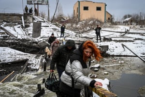 Civilians cross a river on a blown up bridge on Kyivs northern front. Defending capital Kyiv, the “key priority” Ukrainian president said