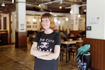 A woman with a bob and the Cure T-shirt smiling in a wooden dining room
