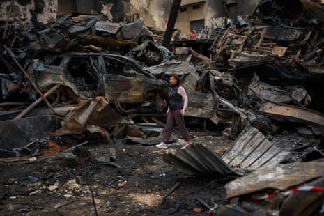 A woman walks near charred cars at the site of an Israeli bombing in Beirut.