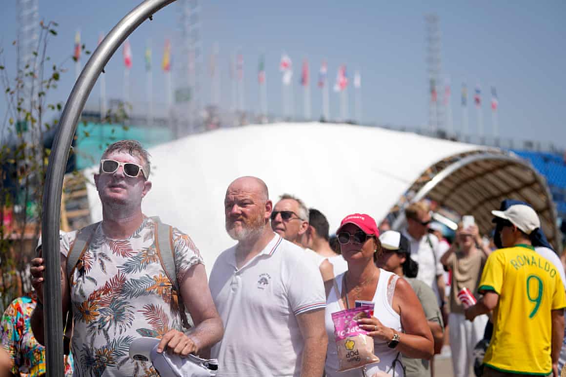 People line up to use a misting fountain on a hot afternoon in Paris, France.