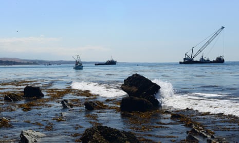 Boat crew members work to clean up oil and oil-impacted marine vegetation from the water near Refugio state beach, north of Goleta, California.